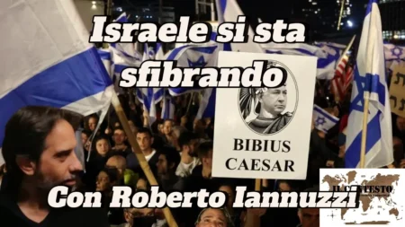 Una folla regge bandiere israeliane e un cartello con la scritta Bibius Caesar durante una protesta per la crisi israeliana.