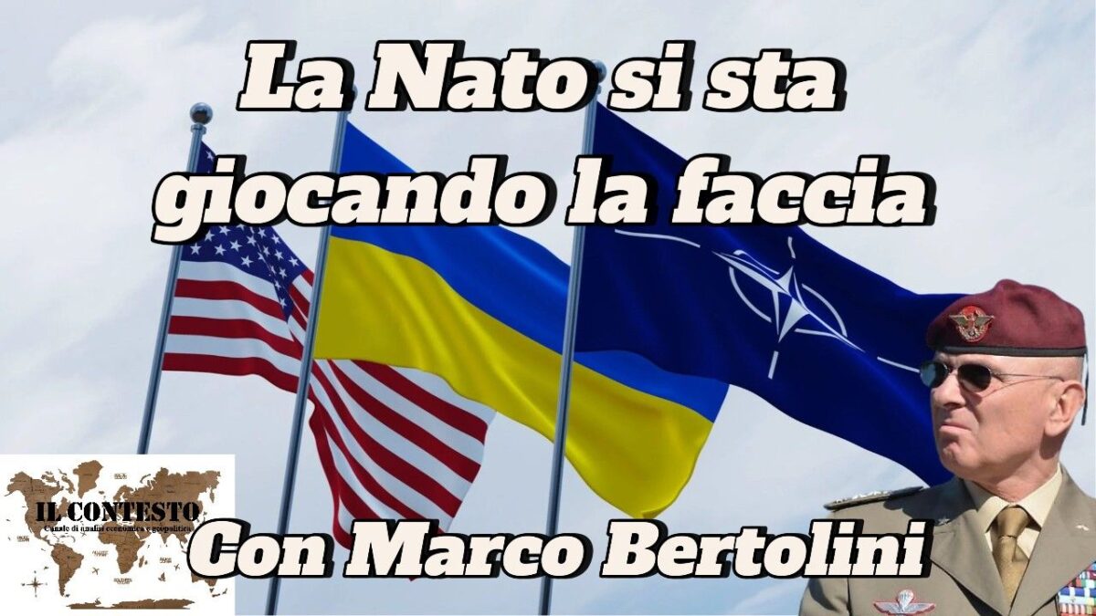 Tre bandiere - USA, Ucraina, NATO - e un uomo in uniforme militare con la scritta 