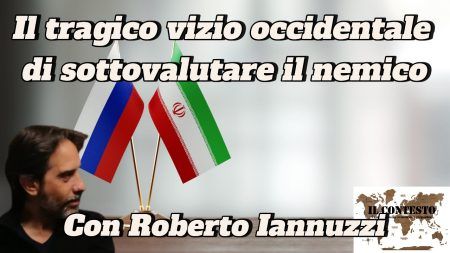 Il tragico vizio occidentale di sottovalutare il nemico Un uomo siede vicino a bandiere russe, iraniane e francesi con la scritta