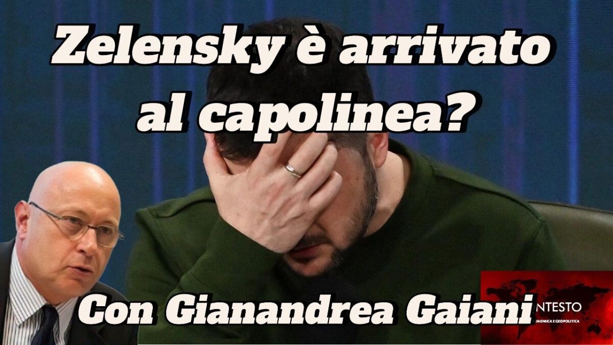 Un uomo si copre il volto con la mano, mentre Zelensky è in piedi nell'angolo del capolinea.