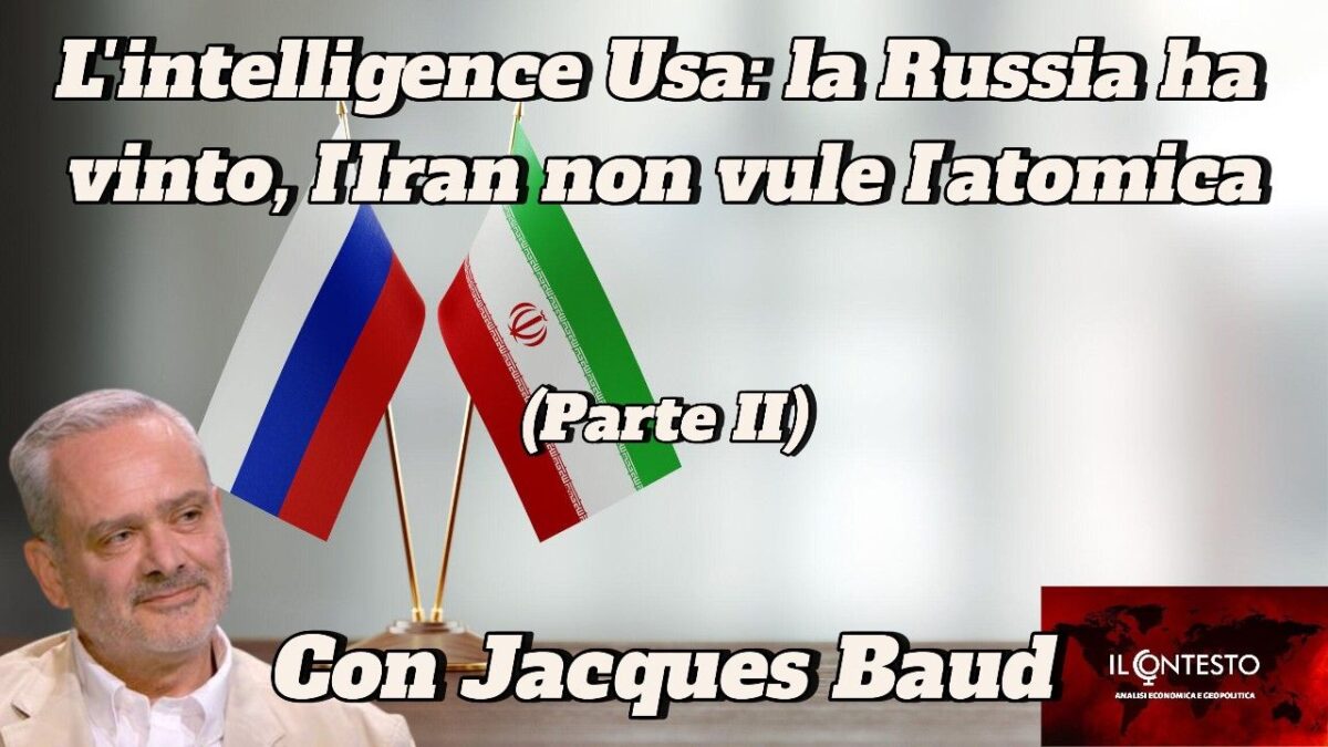 Un uomo siede davanti a bandiere russe e iraniane, discutendo di intelligence statunitense, atomica e Jacques Baud.