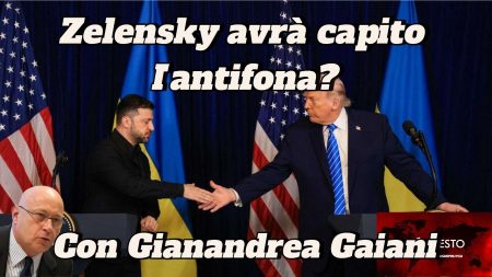 Volodymyr Zelensky e Donald Trump si stringono la mano su un podio, con Viktor Orban in mezzo a bandiere statunitensi e ucraine.